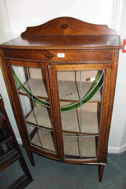 Appraisal: AN EDWARDIAN OAK DISPLAY CABINET of bow front form enclosed