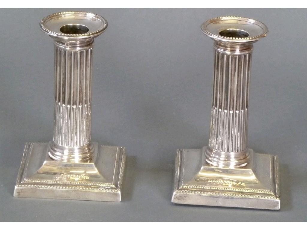 Appraisal: PAIR OF EDWARDIAN SILVER DORIC COLUMN CANDLESTICKS ON SQUARE BASES