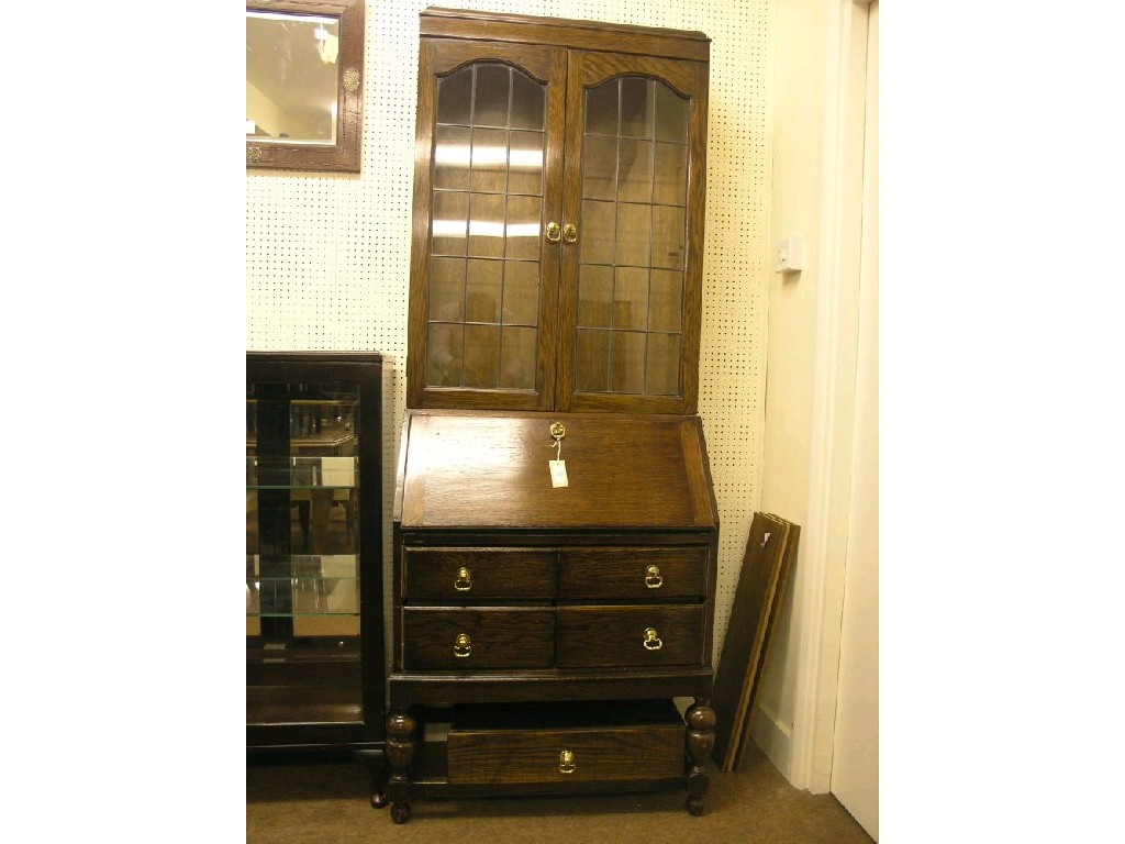 Appraisal: A dark oak bureau bookcase upper stage enclosed by a