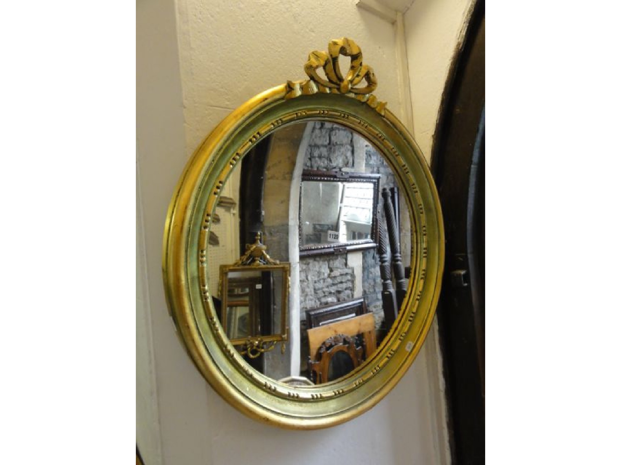 Appraisal: A circular wall mirror with moulded frame tied ribbon surmount