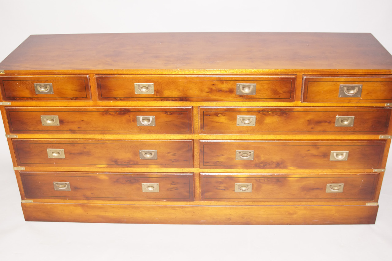 Appraisal: A reproduction yew veneered campaign style low chest of nine