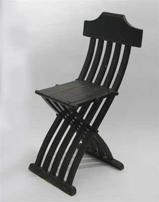 Appraisal: An ebonised wood folding chair decorated with a stamped flowerhead