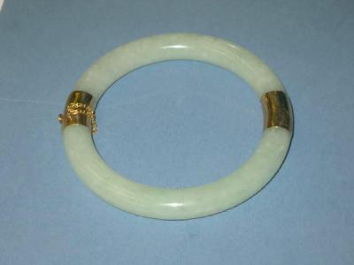 Appraisal: A JADE BANGLE of hinged form the pale green polished