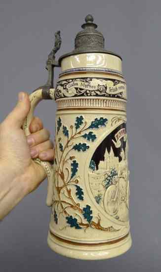 Appraisal: German stein with male and female cyclists '' Ht Good