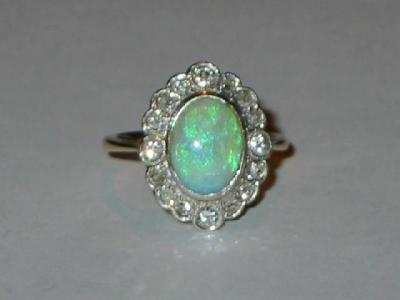 Appraisal: AN OPAL AND DIAMOND CLUSTER RING the oval cabochon opal