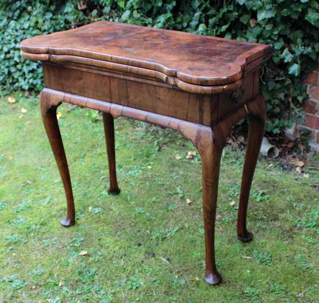 Appraisal: AN EARLY GEORGIAN WALNUT SERPENTINE TOPPED FOLDOVER CARD TABLE the