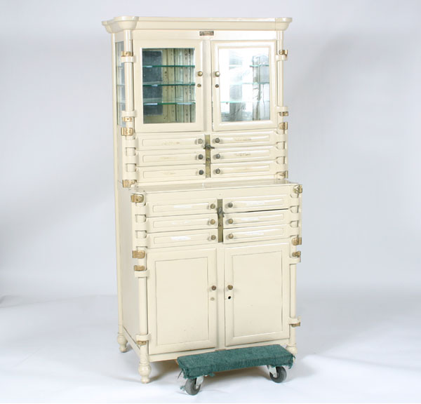 Appraisal: Metal stepback dental cabinet with turned legs and columns sculpted