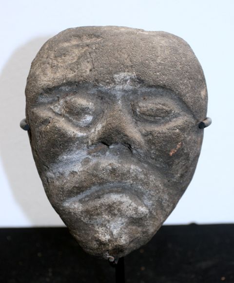 Appraisal: A votive mask carved of volcanic rock on a contemporary