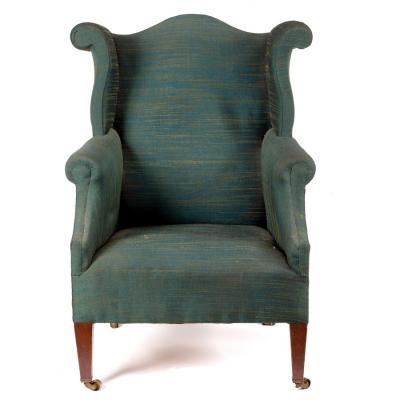 Appraisal: An upholstered wing back armchair with shaped back and scroll