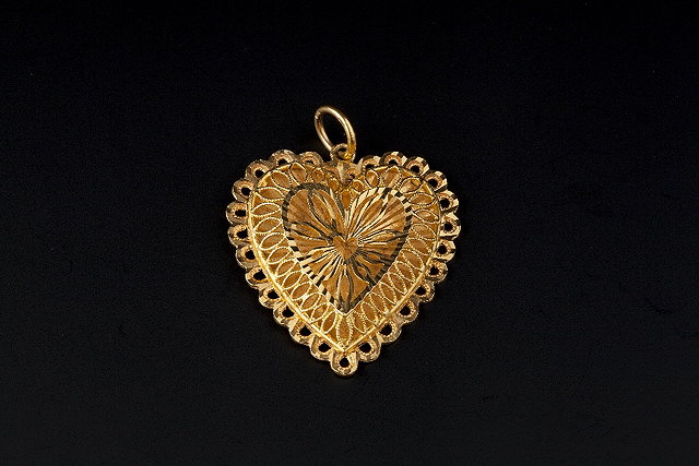 Appraisal: A YELLOW PRECIOUS METAL HEART-SHAPED PENDANT of pierced and engraved