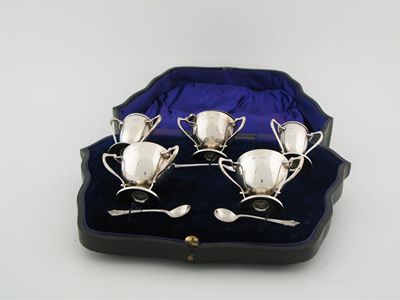 Appraisal: An Edwardian cased condiment set comprising a mustard blue glass