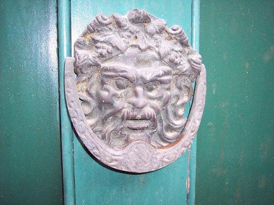 Appraisal: A brass iron door knocker modelled as the mask of