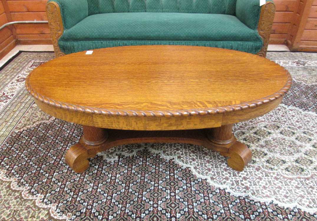 Appraisal: AN OVAL OAK COFFEE TABLE Empire Revival style American c