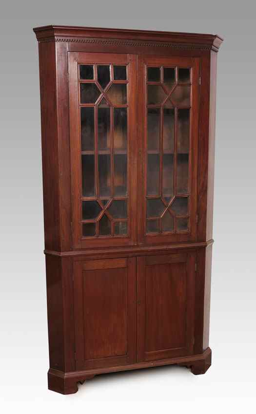 Appraisal: AMERICAN COUNTRY MAHOGANY CORNER CABINET Dentil molding over individually glazed