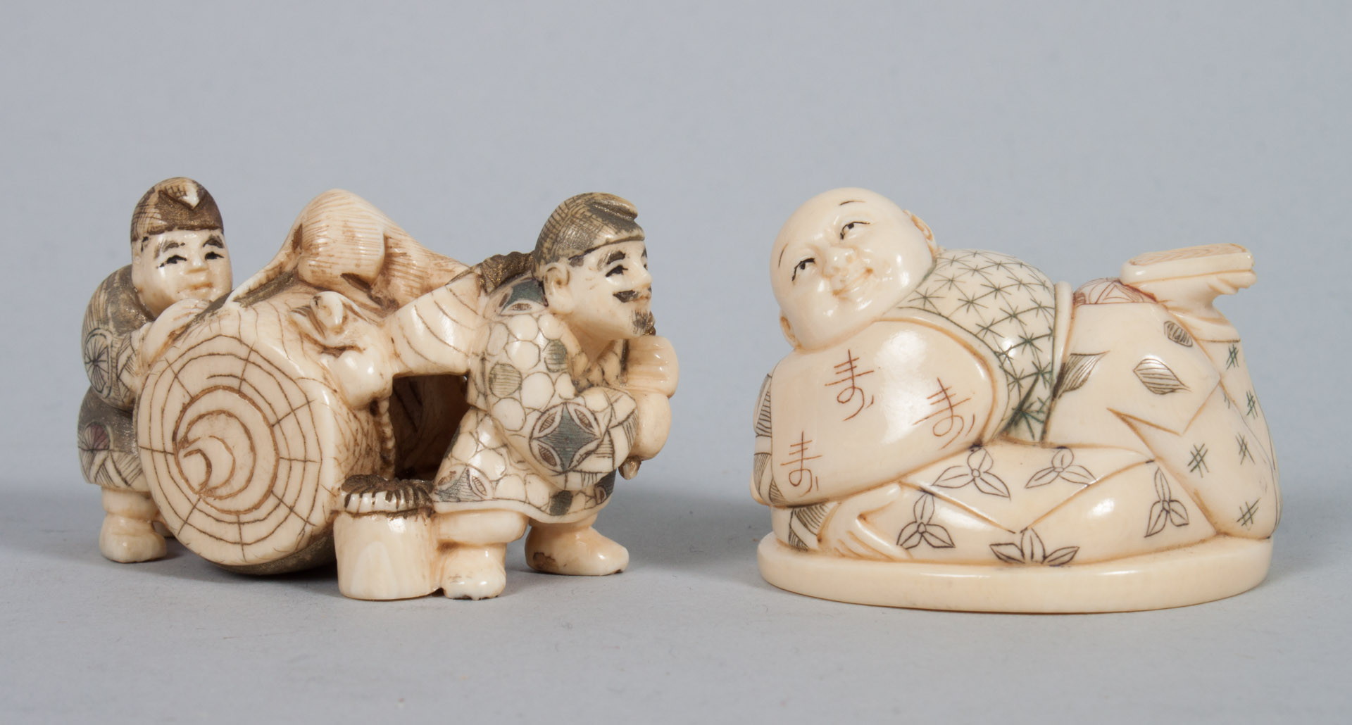 Appraisal: Two Japanese carved ivory netsukes Hotai and two figures rolling