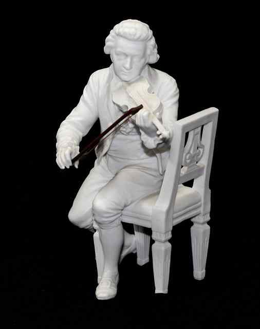 Appraisal: A WHITE BISCUIT CERAMIC MODEL of Mozart seated on a