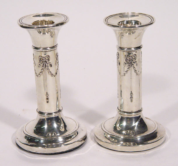 Appraisal: Pair of Edwardian silver circular based candlesticks embossed with bows