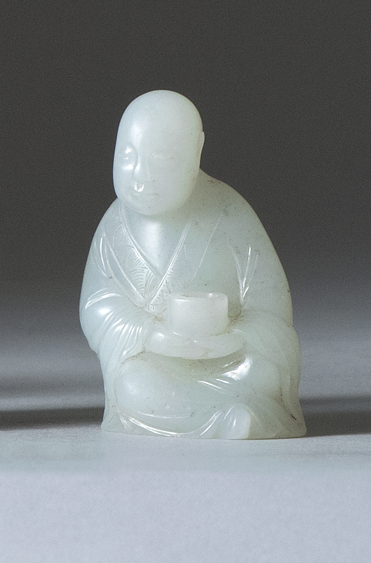 Appraisal: WHITE JADE CARVING Depicting a seated monk holding a beggar's