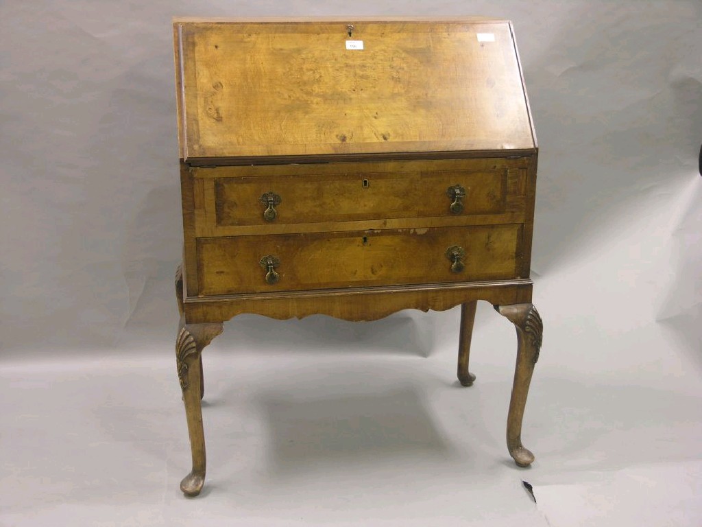 Appraisal: A quarter-veneered burr walnut bureau fall-front enclosing fittings above two