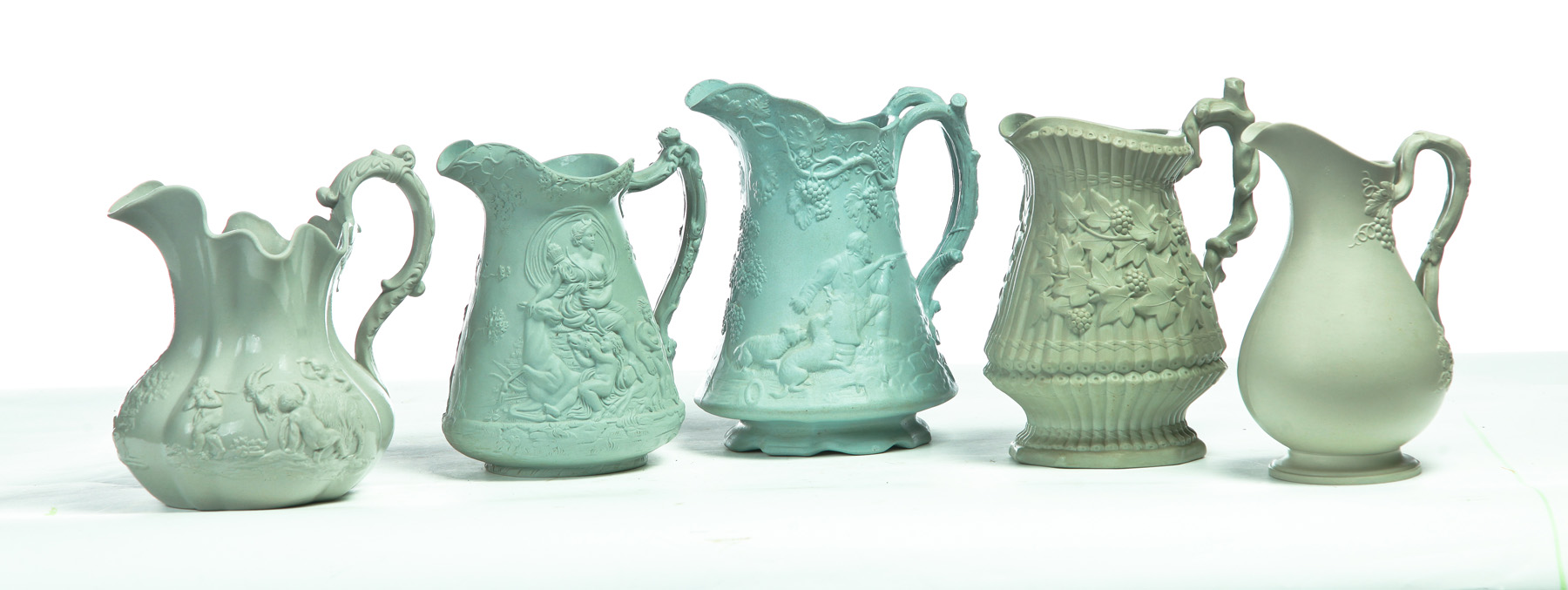 Appraisal: FIVE RELIEF MOLDED SCENIC GREEN PITCHERS English mid th century