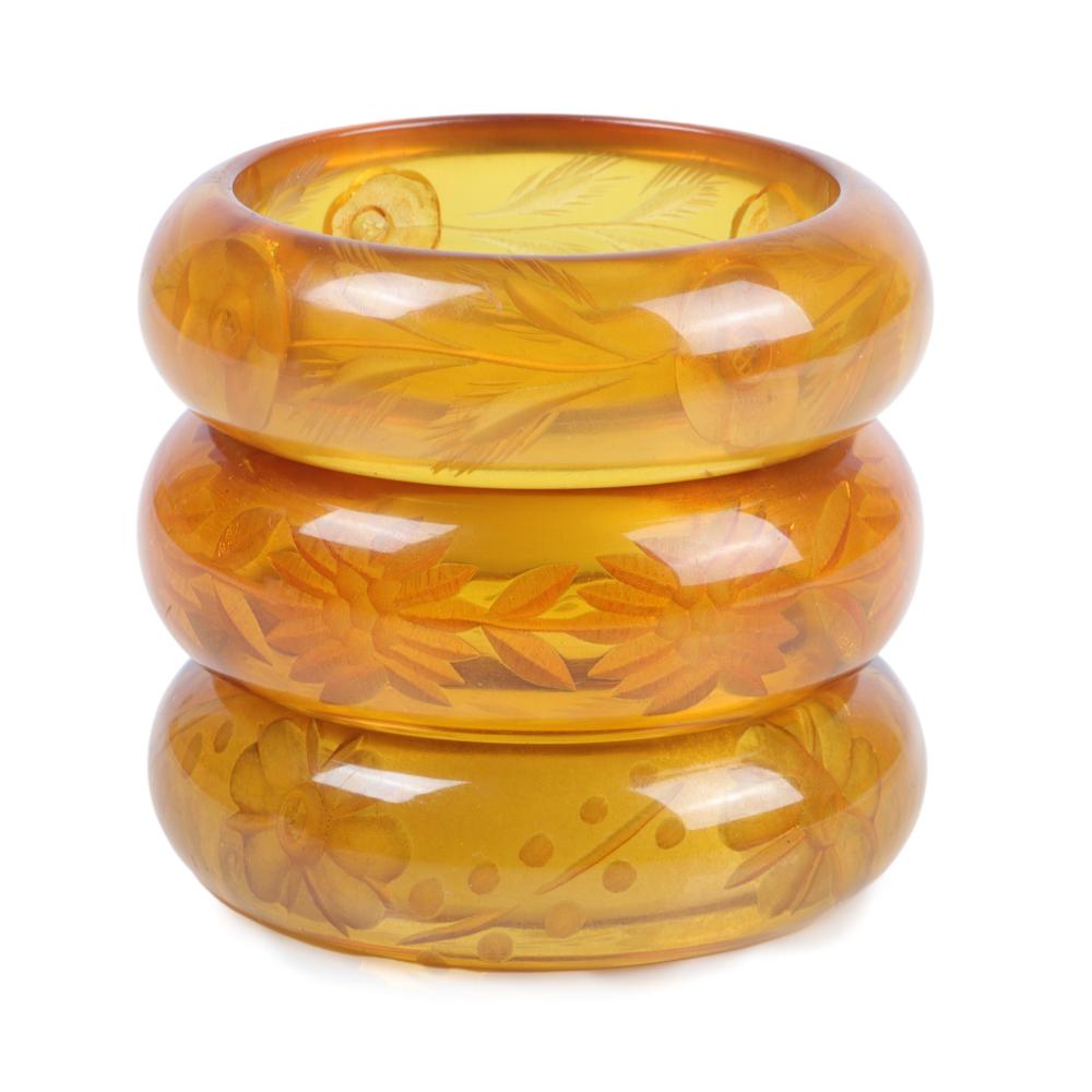 Appraisal: THREE REVERSE CARVED APPLE JUICE BAKELITE BANGLE BRACELETS WITH FLORAL