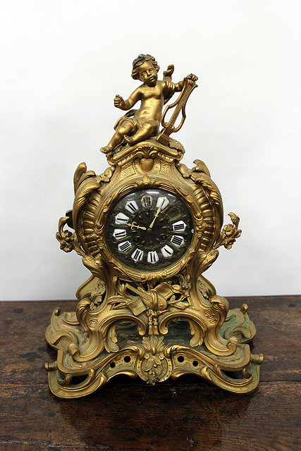 Appraisal: A FRENCH GILT METAL TIMEPIECE the scrolling case surmounted with