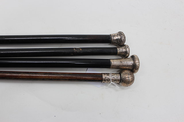 Appraisal: FOUR ANTIQUE SILVER TOPPED WALKING CANES each with tropical hardwood