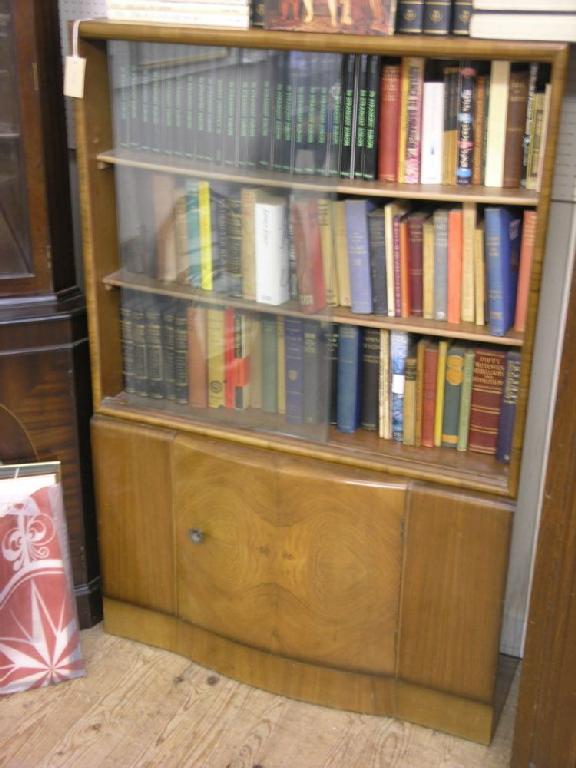 Appraisal: A walnut bookcase enclosed by a pair of sliding glass