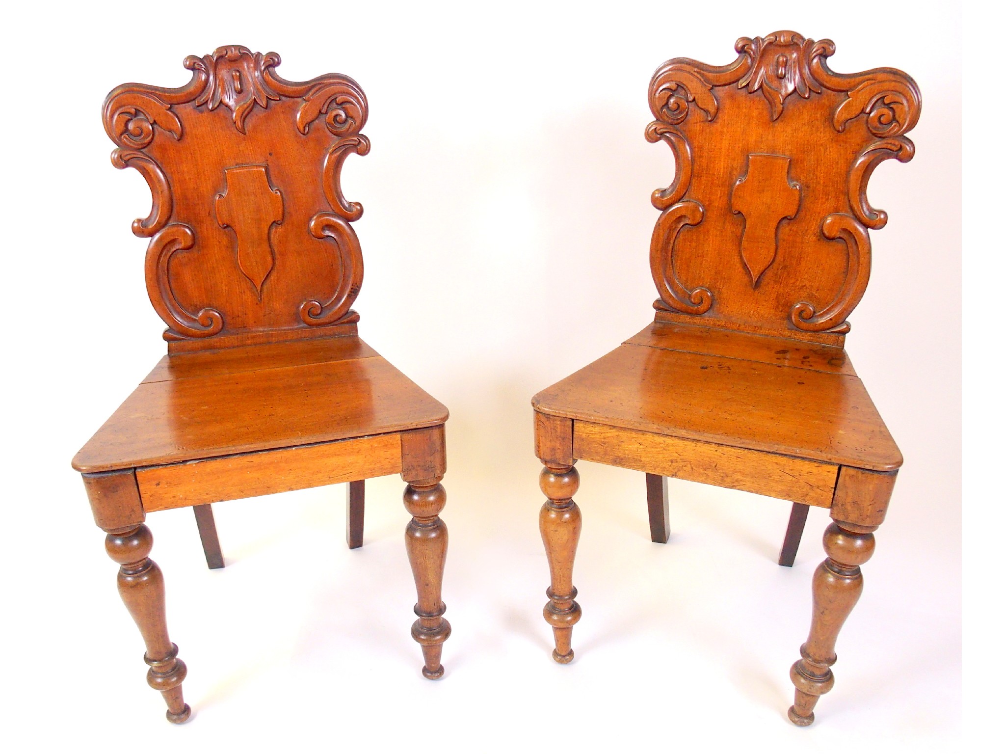 Appraisal: A pair of Victorian mahogany hall chairsthe scroll shaped backs