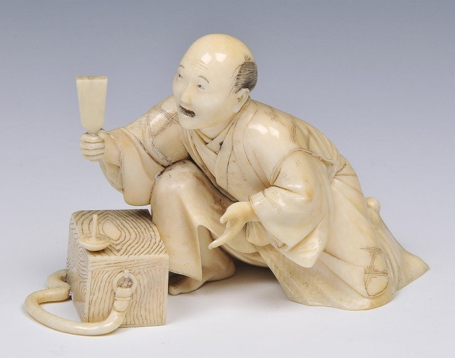 Appraisal: A JAPANESE IVORY OKIMONO of a semi kneeling street entertainer