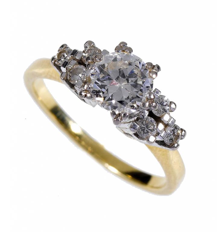 Appraisal: A DIAMOND RING the larger round brilliant flanked by clusters