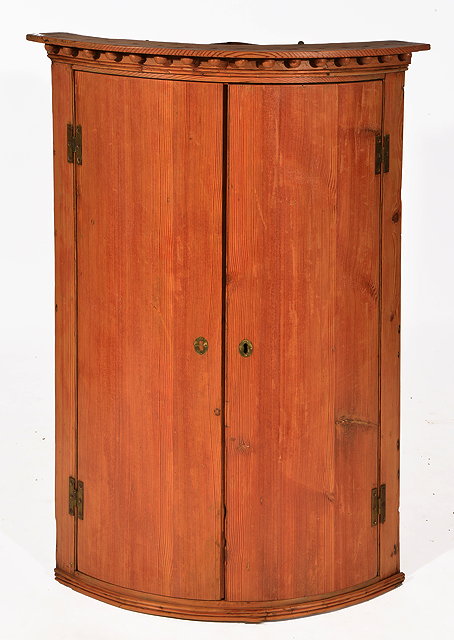 Appraisal: A REGENCY STRIPPED PINE BOW FRONTED HANGING CORNER CUPBOARD the