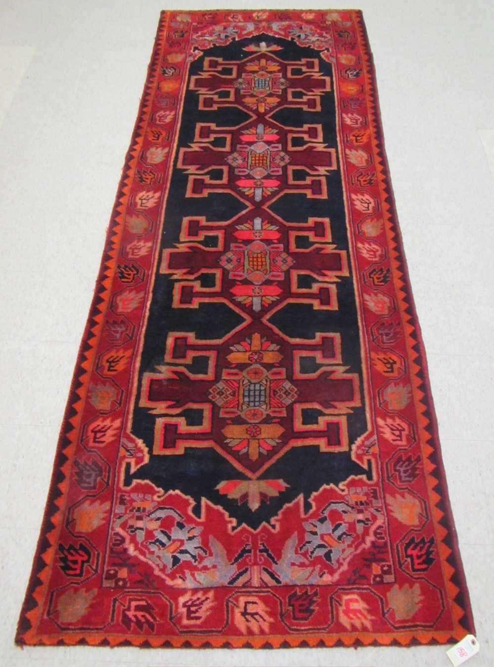 Appraisal: PERSIAN TRIBAL HALL RUG featuring four geometric medallions on midnight