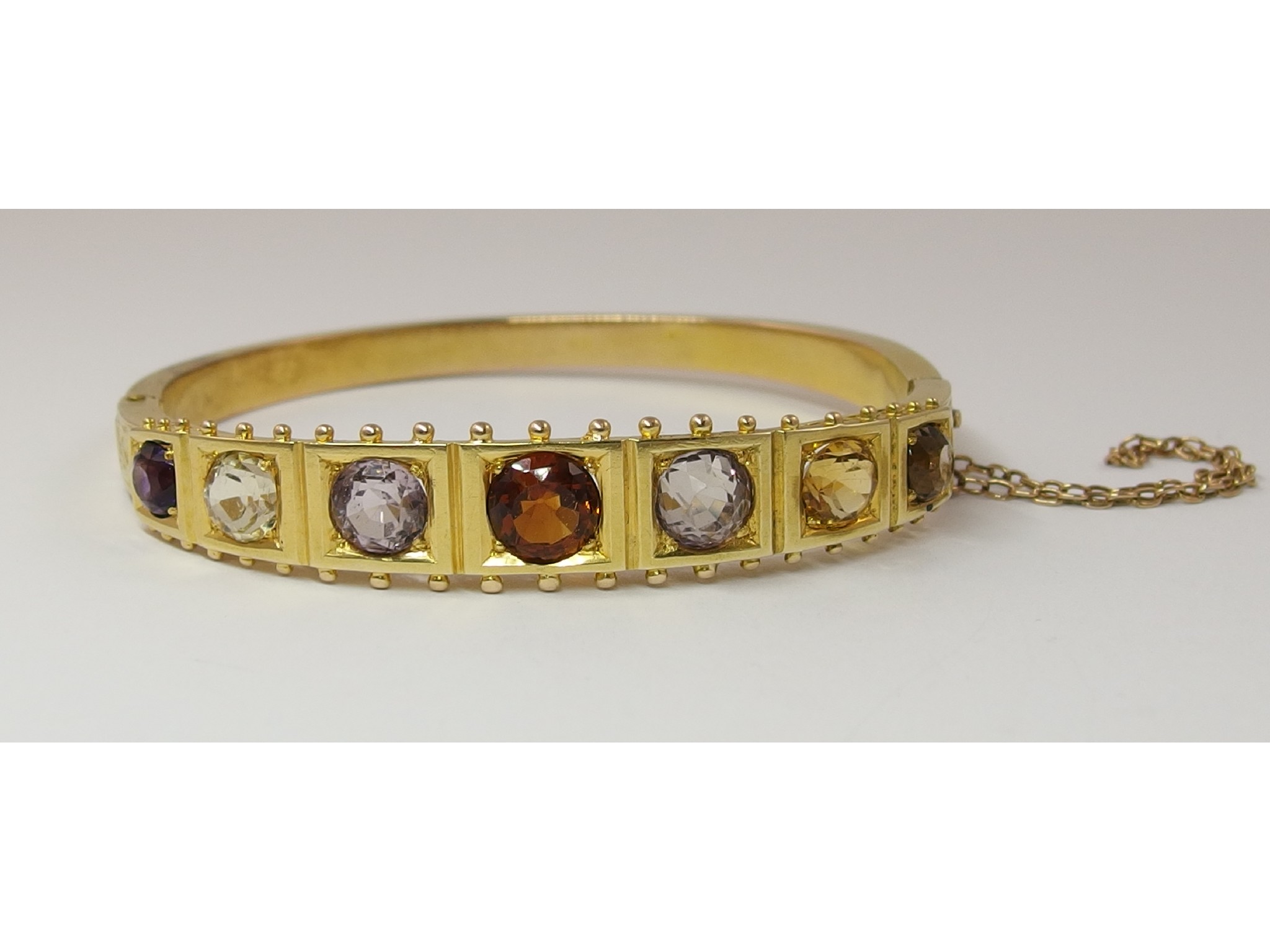 Appraisal: An Edwardian gem set banglethe yellow metal bangle set with