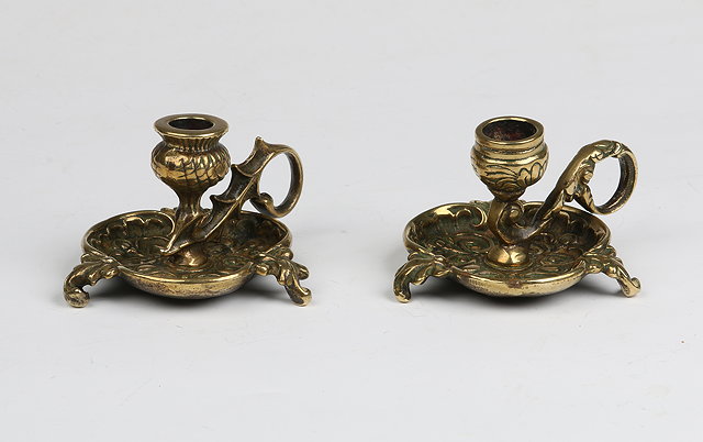 Appraisal: A PAIR OF ANTIQUE BRASS CHAMBER STICKS on trefoil bases