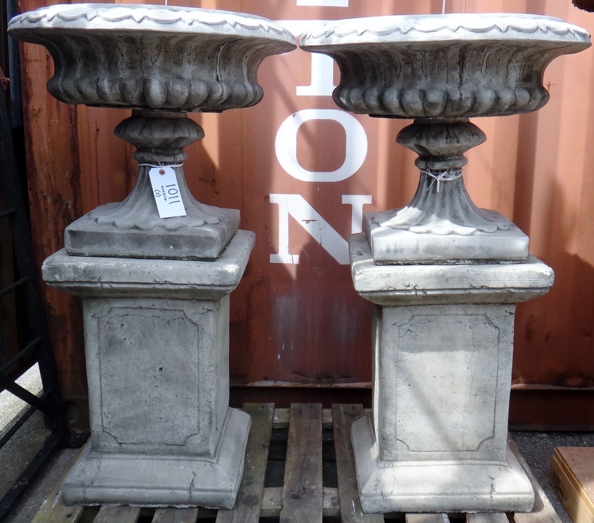 Appraisal: A pair of reconstituted stone shallow urns on fluted soccles