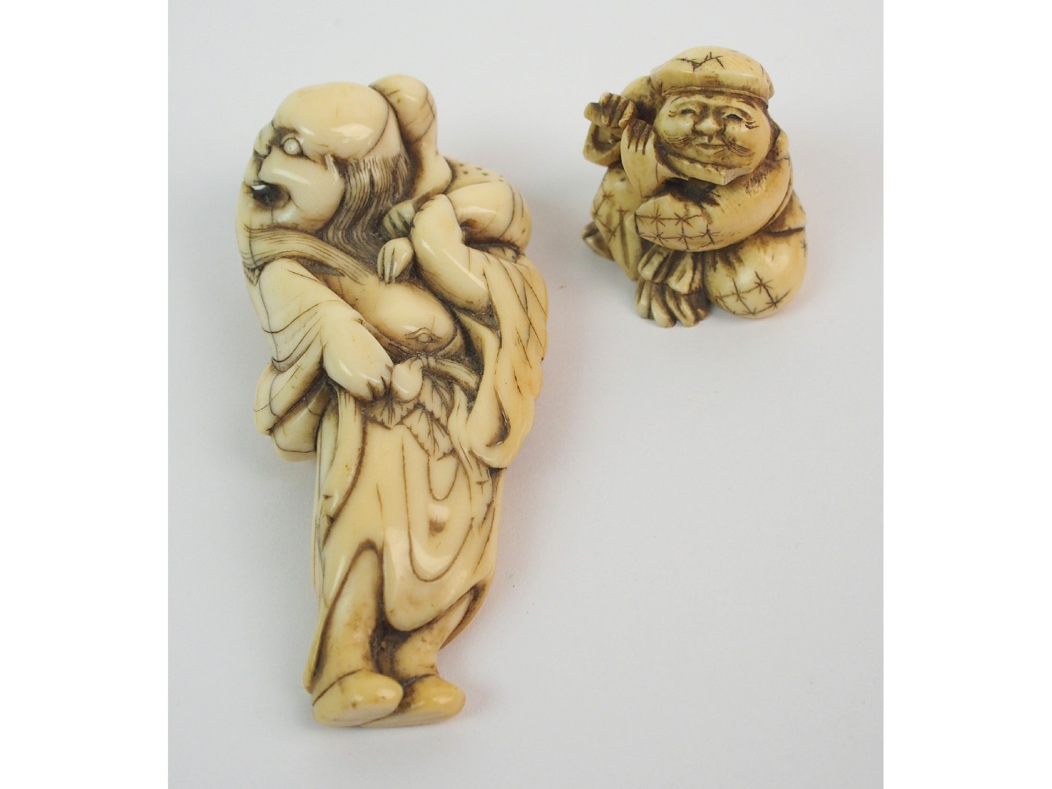 Appraisal: A Japanese ivory netsukeof a grotesque man holding an animal