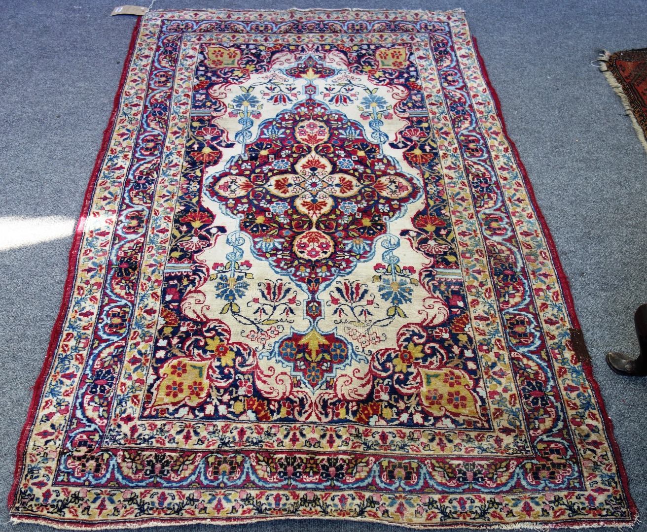 Appraisal: A Kirman rug white ground with central lobed red medallion