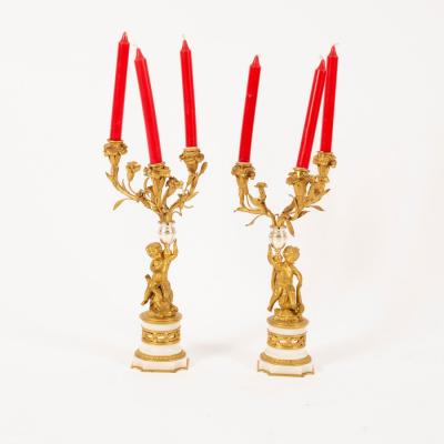 Appraisal: A pair of ormolu three-branch three-light table lights with putto