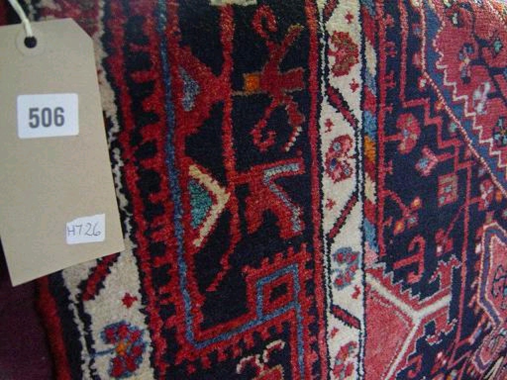 Appraisal: A red ground Eastern wool rug with geometric decoration in