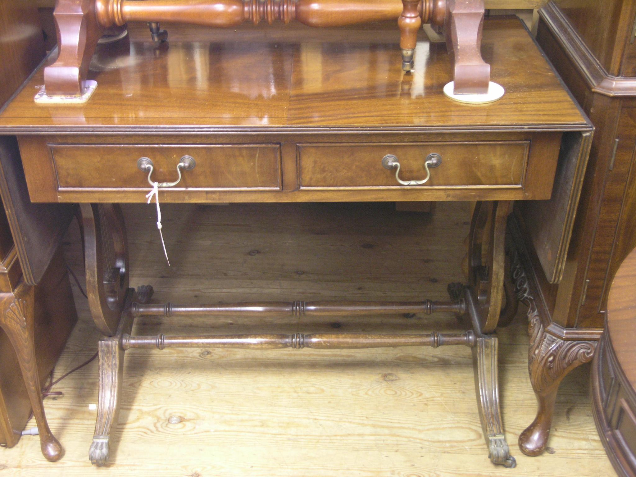 Appraisal: A reproduction mahogany sofa table half-veneered top above two frieze