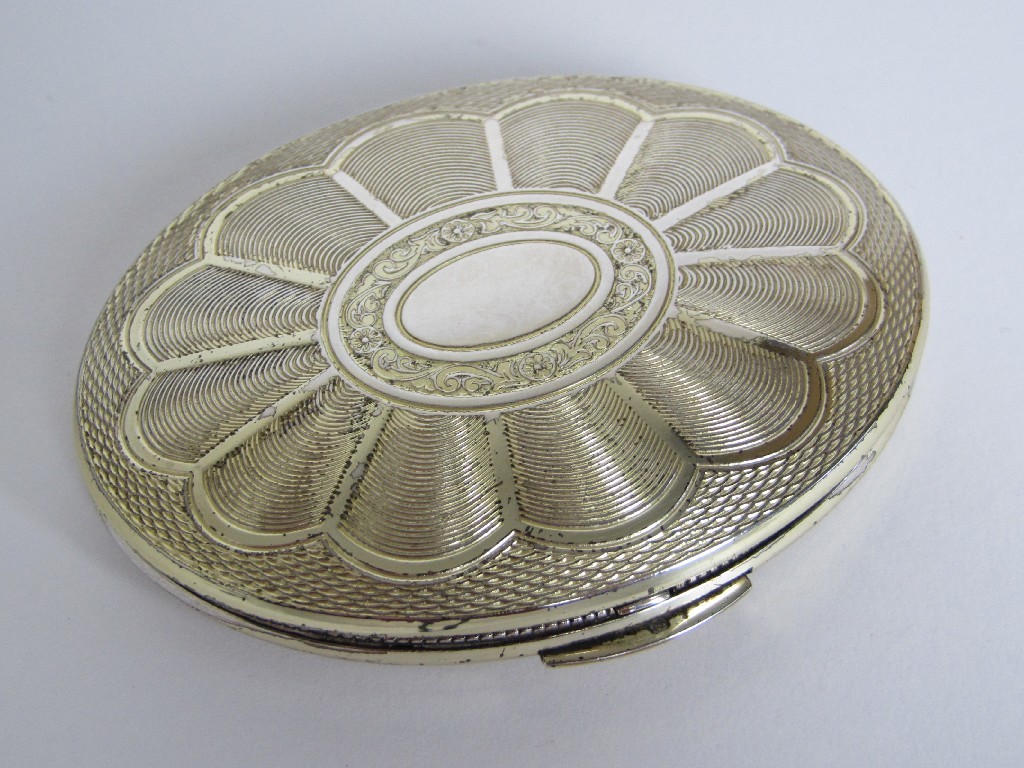 Appraisal: A silver compact of oval form with engine turned decoration