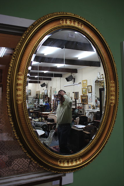 Appraisal: A GILT FRAMED OVAL HANGING WALL MIRROR cm wide x