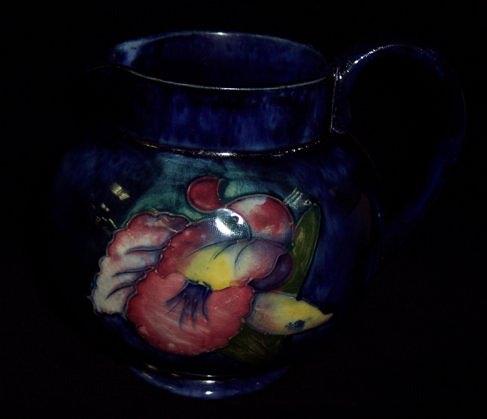 Appraisal: A Moorcroft 'Orchid' jug painted flowers on a dark blue