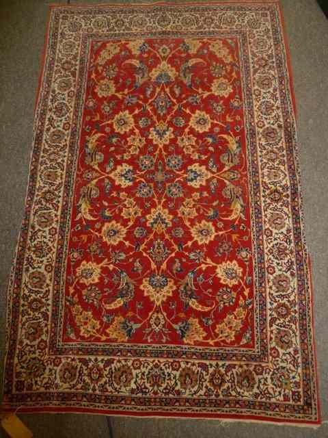 Appraisal: AN IRANIAN RED GROUND RUG with trailing foliage within an