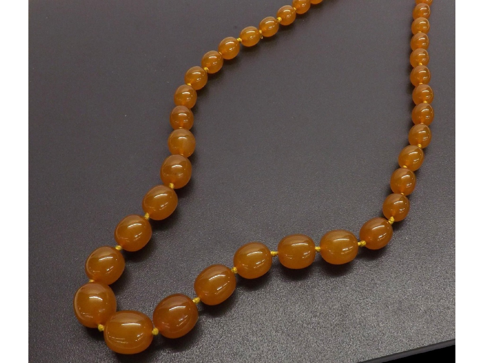 Appraisal: Graduated string of amber oval beads gm largest bead mm