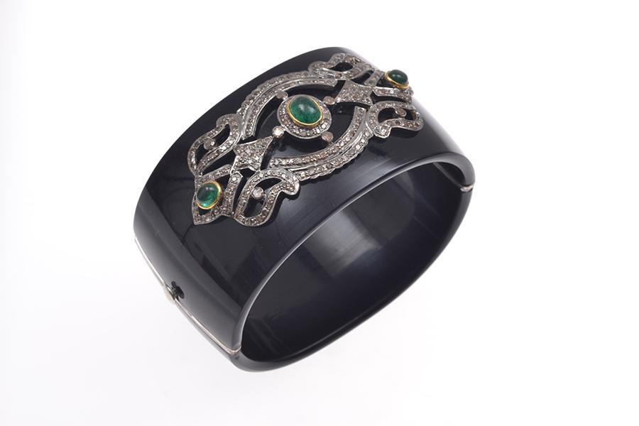 Appraisal: A BAKELITE BANGLE WITH DIAMONDS AND EMERALDS SET IN CT