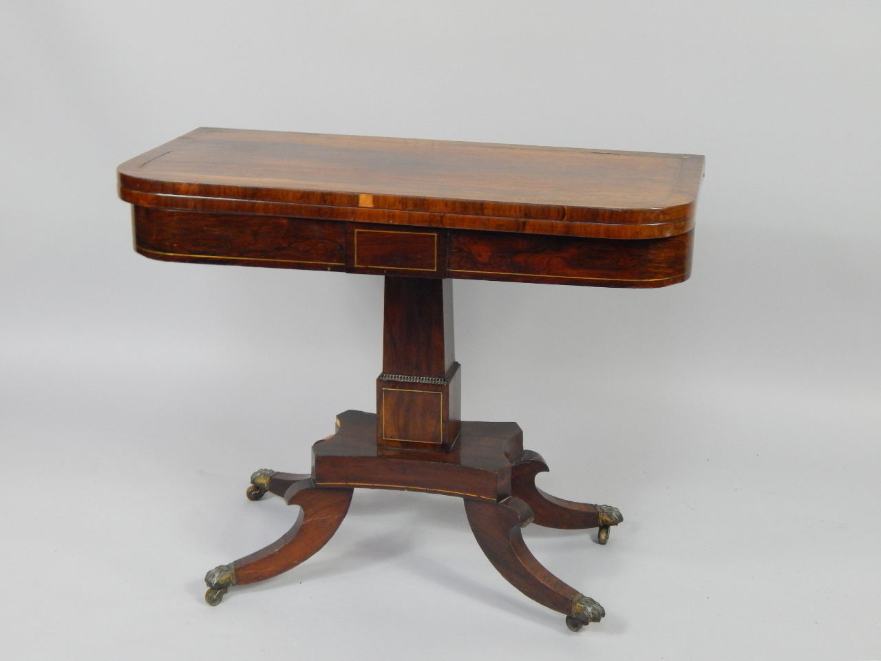 Appraisal: A Regency rosewood and brass inlaid fold over card table