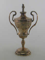 Appraisal: A two handled white metal trophy cup the cover with