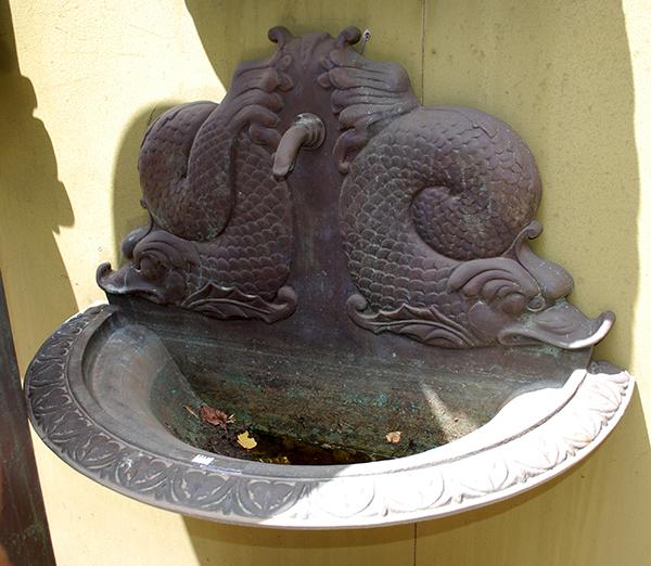 Appraisal: A BRONZE DOLPHIN WALL FOUNTAIN the backplate cast with entwined